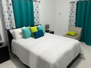 um quarto com uma grande cama branca com almofadas coloridas em Meadows Place em Montego Bay