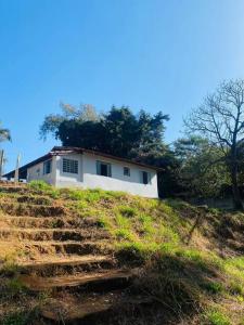 a white house on top of a hill with stairs at Chácara Vale dos Eucaliptos in Pouso Alegre