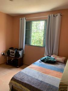 um quarto com uma cama e uma janela em Chácara Vale dos Eucaliptos em Pouso Alegre