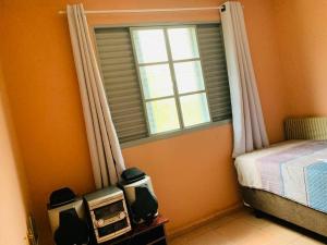 um quarto com uma cama, uma janela e um rádio em Chácara Vale dos Eucaliptos em Pouso Alegre