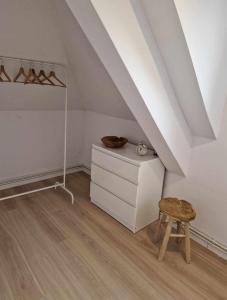 a attic room with a dresser and a stool at Apartamencik Słoneczny in Kamienna Góra