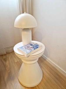 a white lamp with a book on top of a toilet at Apartamencik Słoneczny in Kamienna Góra
