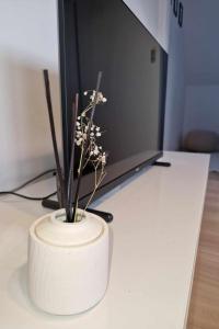 a white vase with flowers in front of a computer monitor at Apartamencik Słoneczny in Kamienna Góra