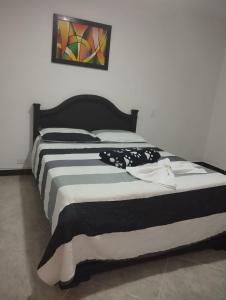 Una cama con una manta blanca y negra encima. en Hotel Confort Boutique, en Rionegro