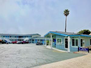 ein blaues Gebäude mit einer Palme auf einem Parkplatz in der Unterkunft Ocean Palms Motel in Pismo Beach