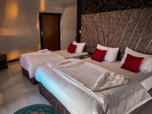 Bacific camp في وادي رم: سريرين في غرفة الفندق مع وسائد حمراء