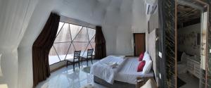 a bedroom with a bed and a large window at Bacific camp in Wadi Rum