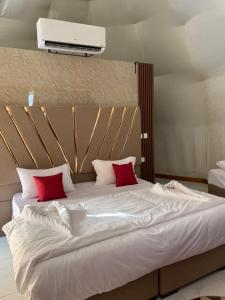 - un grand lit blanc avec 2 oreillers rouges dans l'établissement Bacific camp, à Wadi Rum