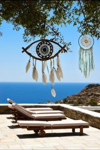 a group of lounge chairs under a tree with the ocean at Villa Giulia, seaview villa in Ios Chora