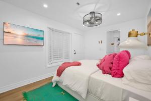 ein weißes Schlafzimmer mit zwei rosa Kissen auf einem Bett in der Unterkunft Chic Modern Designed Home with Private Studio in Newport Beach
