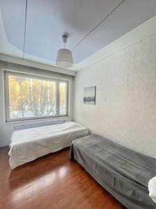 two beds in a room with a window at Nice and cozy big house for 8 people with sauna in Vantaa