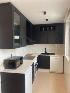eine Küche mit schwarzen Schränken und einer Mikrowelle in der Unterkunft Terraza as Travesas in Betanzos