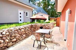 un patio avec une table et des chaises et un mur en pierre dans l'établissement Seeurlaub Müritz - Haus Auszeit mit Sauna, à Röbel