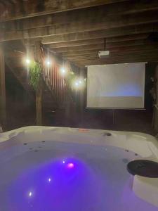 uma grande banheira com um ecrã branco num quarto em Poconos Chalet -Kayaks- HotTub-Karaoke-Lake em East Stroudsburg