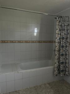 y baño con bañera y cortina de ducha. en Hostal Renacer, en Santa Cruz