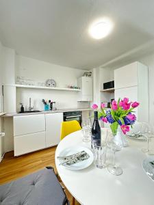 a white kitchen with a table with flowers on it at Cleo Apartments in Kassel
