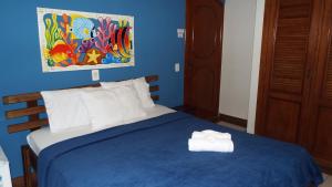 ein blaues Schlafzimmer mit einem Bett mit zwei Handtüchern darauf in der Unterkunft Pousada Quintal do Mar in Ubatuba