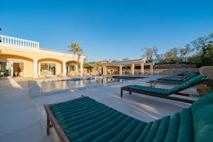 een zwembad met groene ligstoelen naast een gebouw bij Casa Ferrel - Luxury 9 Bedroom Villa with Indoor & Outdoor Pools in Lagos