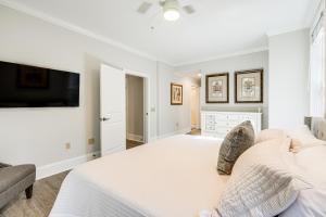 a white bedroom with a bed and a flat screen tv at Chic Greensboro Condo with Lake Oconee Access! in Greensboro