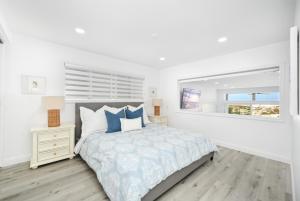 a white bedroom with a bed and a window at 6 Bedroom Remodeled Home on the Oceanfront in Newport Beach