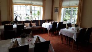 a dining room with white tables and black chairs at Gasthaus Wollmeiner in Schmallenberg