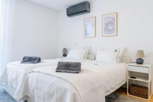 two beds in a white bedroom with towels on them at Beach & Garden Apartment in Ponta Delgada +15 photos