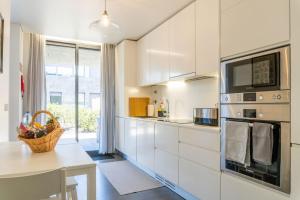 a kitchen with white cabinets and a table and a microwave at Beach & Garden Apartment in Ponta Delgada