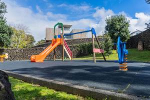 a playground with two swings and a slide at Beach & Garden Apartment in Ponta Delgada