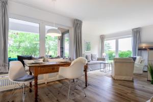 uma sala de estar com uma mesa e cadeiras brancas em Dorfteichblick App 5 em Wenningstedt