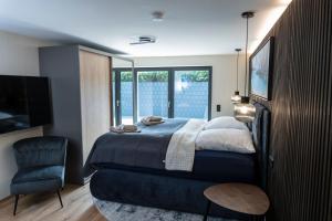 a bedroom with a bed and a chair and a television at Wellness House Oase Spa mit Whirlpool in Timmendorfer Strand