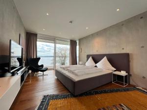 1 dormitorio con 1 cama, TV y silla en Villa am See mit privatem Seezugang en Meersburg