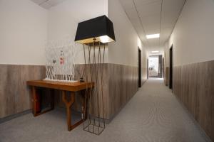 a hallway in a office with a desk and a lamp at Hotel Šumava in Železná Ruda