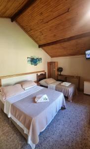 two beds in a room with wooden ceilings at Pousada Portal da Serra - Chalés in Carrancas