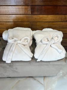 duas toalhas brancas com arcos sobre elas numa cama em Refúgio de Gaia em Chapecó