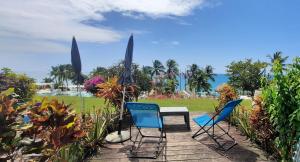 - une terrasse avec 2 chaises, une table et un parasol dans l'établissement Turquoise studio remarquable vue mer, au Diamant