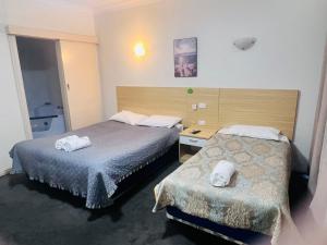 Habitación de hotel con 2 camas y toallas. en Jacksons Motor Inn, en Adelaida