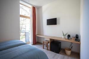a bedroom with a bed and a desk and a window at Locanda della Masseria in Porza