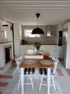 een keuken met een houten tafel en witte stoelen bij Ekbacken - naturskön stuga med närhet till havet in Nyköping