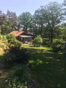 a house in the middle of a yard with trees at Ekbacken - naturskön stuga med närhet till havet in Nyköping