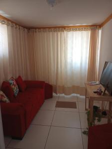 a living room with a red couch and a television at Aconchego da Kika in Caruaru