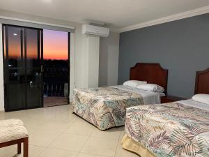 a hotel room with two beds and a large window at Grand Royal Tampico in Tampico