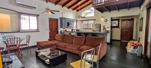 sala de estar con sofá marrón y cocina en Casa Gris in Jaco, en Jacó