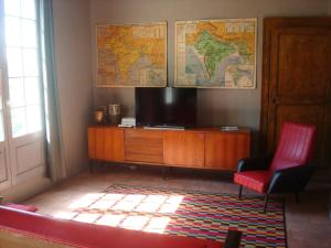 a living room with a tv and a red chair at L'ecole des Filles in Poncé sur Le Loir