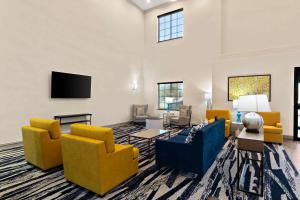 a living room with yellow and blue chairs and a flat screen tv at Comfort Suites in Bastrop