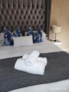1 cama con toallas y cabecero grande en Onyx Luxury cottage, en Randburg