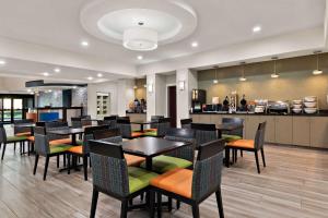 a restaurant with tables and chairs and a kitchen at Comfort Suites in Bastrop