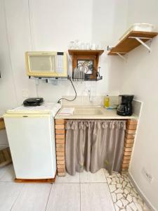 a kitchen with a sink and a microwave at CHALÉ da LÚ ILHABELA in Ilhabela