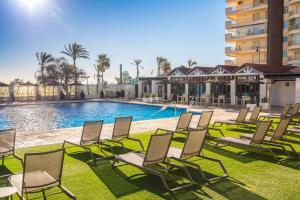 um grupo de cadeiras sentadas ao lado de uma piscina em Occidental Fuengirola em Fuengirola