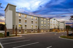 ein großes weißes Gebäude mit Parkplatz in der Unterkunft WoodSpring Suites Port Orange - Daytona Beach in Port Orange