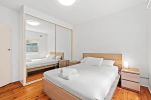 a bedroom with a large white bed and a mirror at Leafy Family House, Close to Beach and Surf Club in Macmasters Beach